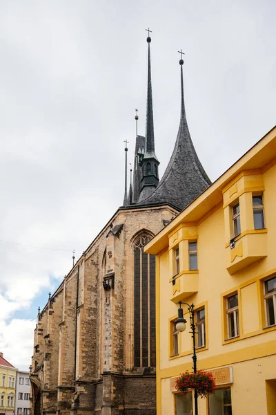Louny, Çek Cumhuriyeti, 19 Eylül 2021: Gotik yüksek saat kulesine sahip Ortaçağ Katolik taş kilisesi, tarihi şehir merkezinde dar resimli cadde, kemerler 