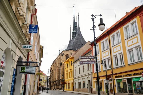 Louny, Çek Cumhuriyeti, 19 Eylül 2021: Gotik yüksek saat kulesine sahip Ortaçağ Katolik taş kilisesi, tarihi şehir merkezinde dar resimli cadde, kemerler 