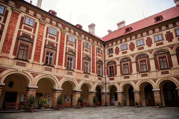 Libochovice, Bohemya, Çek Cumhuriyeti, 19 Eylül 2021: Fransız tarzı park ve bahçeli kale, Romantik kırmızı ve sarı barok şato, sonbahar günü atari salonlu avlu, seramik kaplarda bitkiler