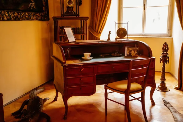 Libochovice, Bohemya, Çek Cumhuriyeti, 19 Eylül 2021: Barok ahşap mobilyalar, yazı masası ve sandalye, kitaplar, aile fotoğrafı ve pencerelerin yanındaki masada beyaz porselen bardak