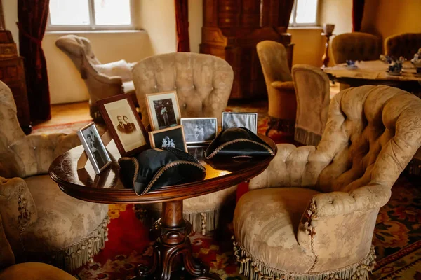 Libochovice, Bohemya, Çek Cumhuriyeti, 19 Eylül 2021: Barok ahşap oymalı mobilya ile kale iç mimarisi, yumuşak püsküllü koltuklu misafir salonu, aile fotoğrafları ve tricorne şapkalı masa