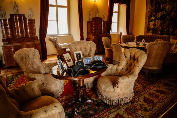 Libochovice, Bohemya, Çek Cumhuriyeti, 19 Eylül 2021: Barok ahşap oymalı mobilya ile kale iç mimarisi, yumuşak püsküllü koltuklu misafir salonu, aile fotoğrafları ve tricorne şapkalı masa