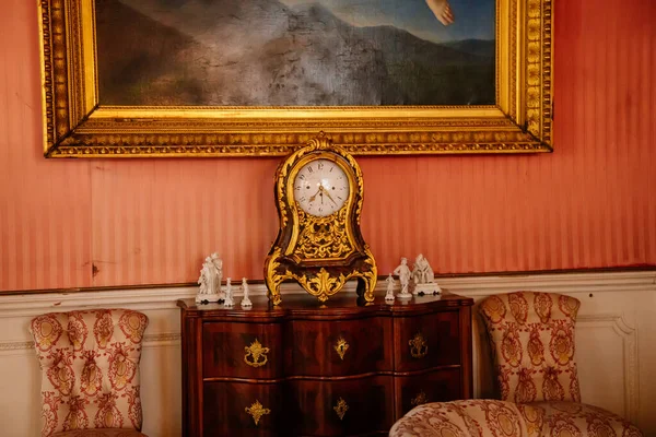 Libochovice, Bohemia, Çek Cumhuriyeti, 19 Eylül 2021: Barok ahşap mobilyalar, çekmeceli şifoniyerde altın kaplama antika saat, duvarda altın çerçeveli resim