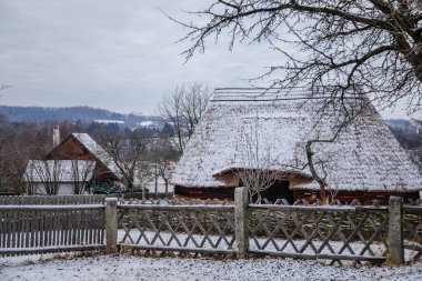 Kourim, Czech Republic, 26 December 2021: Traditional village wooden timbered barn with low walls and steep thatched roof in winter, historic country-style architecture, open-air ethnographic museum
