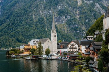 Hallstatt, Avusturya, 27 Ağustos 2021: Yaz günü renkli manzaralı bir kasaba sokağı, göl, Alpler, Lüteryen Kilisesi, UNESCO mirası, geleneksel tarihi evler, su gölü yakınlarındaki bir dağ köyü
