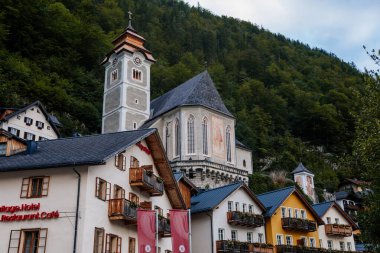 Hallstatt, Avusturya, 27 Ağustos 2021: Yaz günü renkli manzaralı bir kasaba sokağı, göl kenarındaki dağ köyü, Alpler, Katolik Varsayım Kilisesi, UNESCO mirası, geleneksel evler