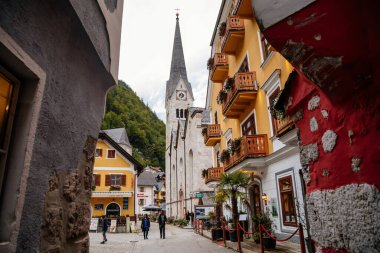 Hallstatt, Avusturya, 27 Ağustos 2021: Yaz günü renkli manzaralı bir kasaba sokağı, göl, Alpler, Lüteryen Kilisesi, UNESCO mirası, geleneksel tarihi evler, su gölü yakınlarındaki bir dağ köyü