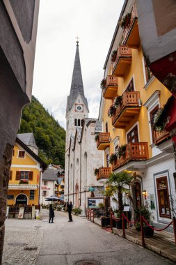 Hallstatt, Avusturya, 27 Ağustos 2021: Yaz günü renkli manzaralı bir kasaba sokağı, göl, Alpler, Lüteryen Kilisesi, UNESCO mirası, geleneksel tarihi evler, su gölü yakınlarındaki bir dağ köyü