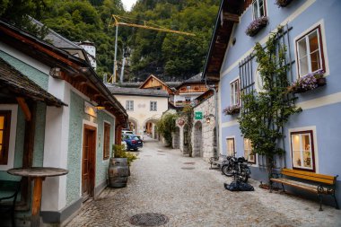 Hallstatt, Avusturya, 27 Ağustos 2021: Yaz günü renkli manzaralı bir kasaba sokağı, göl ve Alpler yakınlarındaki dağ köyü, UNESCO mirası, geleneksel evler, ahşap balkonlar, saksılarda çiçekler