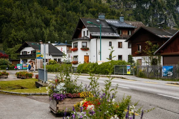Hallstatt, Avusturya, 27 Ağustos 2021: Yaz günü renkli manzaralı bir kasaba sokağı, göl ve Alpler yakınlarındaki dağ köyü, UNESCO mirası, geleneksel evler, ahşap balkonlar, saksılarda çiçekler