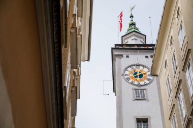 Salzburg, Avusturya, 28 Ağustos 2021: Tarihi Altstadt 'ta Tahıl Şeridi veya Getreidegasse alışveriş dar sokağı, yaz günü demir lonca tabelası, saat kulesi olan Rathaus Eski Belediye Binası