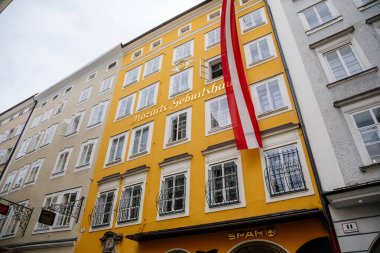 Salzburg, Avusturya, 28 Ağustos 2021: Ortaçağ şehrinde, Rönesans ve Barok evlerinde, Mozart 'ın doğduğu sarı evin ön cephesinde, tarihi merkezlerinde renkli binalar bulunan dar resimli cadde