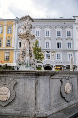 Linz, Avusturya, 27 Ağustos 2021: Barok Neptunbrunnen Çeşmesi 'nde yunus heykelleri, Hauptplatz veya güneşli yaz gününde ana meydan, taş renkli tarihi binalar cephesi