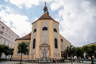 Linz, Avusturya, 27 Ağustos 2021: Ortaçağ Katolik Barok Stadtpfarrkirche with tower, Parish Church at Pfarrplats, eski şehir caddesi, güneşli yaz günü, taş gotik ve rönesans binaları cephesi