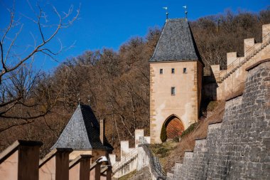 Karlstejn, Bohemya, Çek Cumhuriyeti, 12 Mart 2022: Kral 4. Charles tarafından kurulan eski bir ortaçağ Gotik kalesi, güneşli bahar gününde mavi gökyüzü, ünlü bir dönüm noktası, güçlendirilmiş surlar.