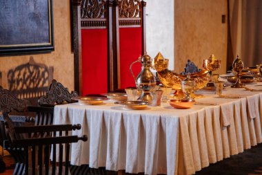 Karlstejn, Çek Cumhuriyeti, 12 Mart 2022: Ortaçağ Gotik kalesi iç mimarisi, antik ahşap oyma mobilya, yemek odası veya büyük salon altın sürahi ve masa takımı, eski sandalyeler