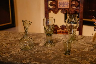 Karlstejn, Bohemya, Çek Cumhuriyeti, 12 Mart 2022: Ortaçağ Ortaçağ tarihi şarap kadehinin tarihi kopyası masanın üstünde, ortaçağ Gotik kalesinin iç kısmı, antik ahşap oyma mobilyalar, yemek odası 