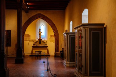 Karlstejn, Çek Cumhuriyeti, 12 Mart 2022: Ortaçağ Gotik kalesi iç mimarisi, antik ahşap mobilyalar, ahşap Aziz Nicholas figürlü antik sunak ve mumlar, duvarlarında ikonlar olan büyük salon.