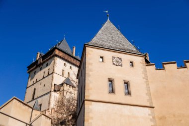 Karlstejn, Bohemya, Çek Cumhuriyeti, 12 Mart 2022: Kral 4. Charles tarafından kurulan eski bir ortaçağ Gotik kalesi, güneşli bahar gününde mavi gökyüzü, ünlü bir dönüm noktası, güçlendirilmiş surlar.