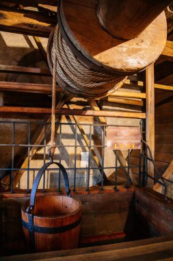 Karlstejn, Çek Cumhuriyeti, 12 Mart 2022: Ortaçağ Gotik şatosu iç mimarisi, antik ahşap oyma mobilyalar, ahşap bir kova ve kule içinde kaldırma tekerleği.