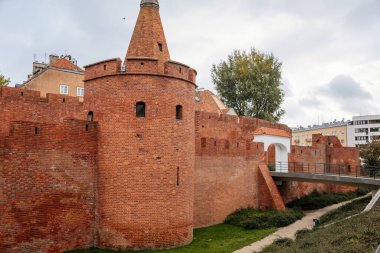 Varşova, Polonya, 13 Ekim 2021: Eski ve Yeni Şehir arasında tarihi tahkimat ağları, kuleleri olan kırmızı tuğlalı kale duvarı, güneşli sonbahar gününde büyük turistik cazibe, şehir kapısı