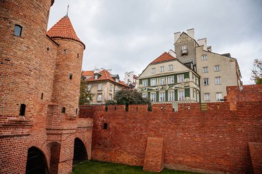 Varşova, Polonya, 13 Ekim 2021: Eski ve Yeni Şehir arasında tarihi tahkimat ağları, kuleleri olan kırmızı tuğlalı kale duvarı, güneşli sonbahar gününde büyük turistik cazibe, şehir kapısı