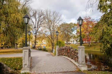 Riga, Letonya, 19 Ekim 2021: Güneşli bir sonbahar gününde Letonya Ulusal Operası yakınlarındaki güzel Bastejkalna Central Park, su üzerinde köprü