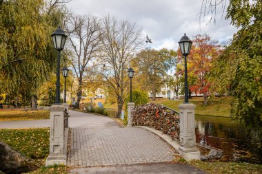 Riga, Letonya, 19 Ekim 2021: Güneşli bir sonbahar gününde Letonya Ulusal Operası yakınlarındaki güzel Bastejkalna Central Park, su üzerinde köprü