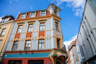 Riga, Letonya, 14 Ekim 2021: Güneşli bir günde modern ve sanat dekoltesi stillerinin dekoratif unsurları ve heykelleri ile eski kentteki renkli konut sanatının yeni binasının güzel cephesi