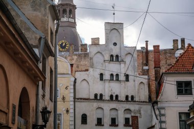 Riga, Letonya, 14 Ekim 2021: Dar resimli cadde, ortaçağ şehrinin tarihi merkezinde renkli binalar cephesi, yaz güneşli bir günde rönesans ve barok evler, ahşap pencereli kafe