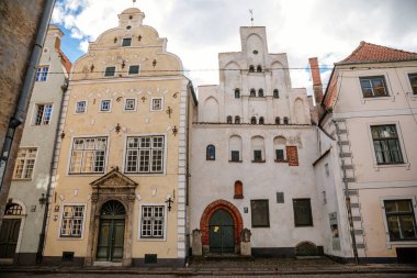 Riga, Letonya, 14 Ekim 2021: Dar resimli cadde, ortaçağ şehrinin tarihi merkezinde renkli binalar cephesi, yaz güneşli bir günde rönesans ve barok evler, ahşap pencereli kafe