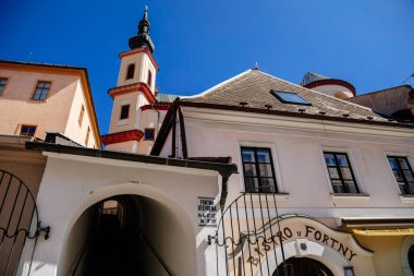 Litomysl, Çek Cumhuriyeti, 17 Nisan 2022: Güneşli yaz gününde ortaçağ renkli gotik ticaret evleri, tarihi rönesans ve barok binaları ve ortaçağ kilisesi olan dar resim caddesi