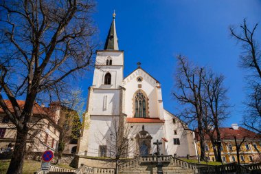 Litomysl, Çek Cumhuriyeti, 17 Nisan 2022: Güneşli yaz gününde kulesi, St. Marquette Kilisesi, taş heykeller ile Kutsal Haç 'ın Gotik Ortaçağ Kilisesi