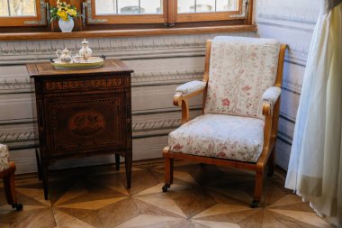 Litomysl, Çek Cumhuriyeti, 17 Nisan 2022: Barok ahşap mobilya, antika kanepe ve pencerenin yanında yumuşak koltuklar, masa başında porselen çay seti bulunan şato, oturma veya yemek odası