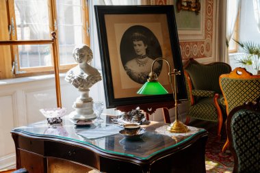 Litomysl, Çek Cumhuriyeti, 17 Nisan 2022: Barok klasik mobilyaları, tahta yazı masası ve pencerelerin yanındaki sandalye, Elizabeth Bavyera 'nın portresi, yeşil tonlu lamba