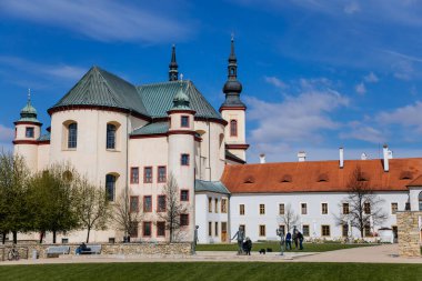 Litomysl, Çek Cumhuriyeti, 17 Nisan 2022: Kutsal Haç 'ı Bulma Kilisesi ve kalenin yakınındaki Piarist yatakhanesi, güneşli yaz gününde kulesi olan barok bina, Manastır Bahçesi Çeşmesi