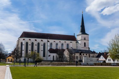 Litomysl, Çek Cumhuriyeti, 17 Nisan 2022: Güneşli yaz gününde kulesi, Manastır Bahçesi Çeşmesi, taş ve bronz heykelleri olan Orta Çağ Kutsal Haç 'ın Yüceltilmesi Kilisesi