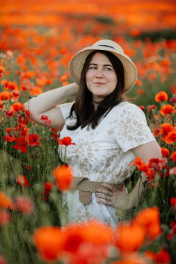 Scenic picturesque of beautiful girl in white and beige dress and straw hat in poppy field at sunset, Portrait of romantic young woman with flowers, body positivity, Selective focus natural light