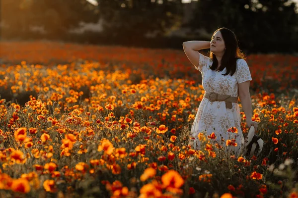 Beyaz ve bej elbiseli güzel bir kızın gün batımında haşhaş tarlasında saman şapkalı güzel bir kızın resmi, çiçekli romantik genç bir kadının portresi, pozitiflik, seçici doğal ışık.
