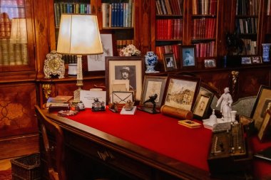 Slatinany, Czech Republic, 17 April 2022:  Castle chateau representative interior with baroque wooden carved furniture, writing table or desk and bookshelves, Photos and figurines, lamp and documents