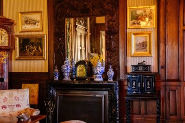 Slatinany, Czech Republic, 17 April 2022:  Castle chateau representative interior with baroque wooden carved furniture, Chinese porcelain vases and antique clocks on mantelpiece, large mirror