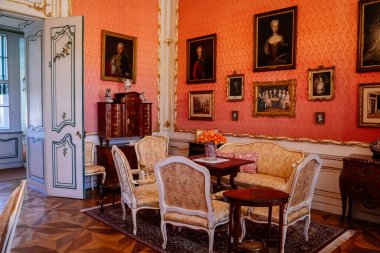 Slatinany, Czech Republic, 17 April 2022:  Castle chateau representative interior with baroque wooden carved furniture, sofa and armchairs, table with porcelain dishes, paintings and photographs