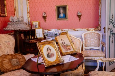 Slatinany, Czech Republic, 17 April 2022:  Castle chateau representative interior with baroque wooden carved furniture, sofa and armchairs, table with porcelain dishes, paintings and photographs