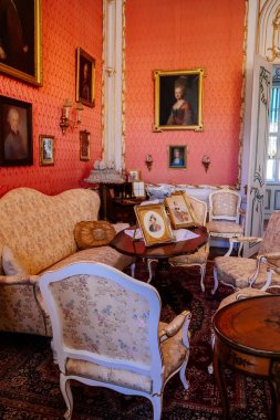 Slatinany, Czech Republic, 17 April 2022:  Castle chateau representative interior with baroque wooden carved furniture, sofa and armchairs, table with porcelain dishes, paintings and photographs
