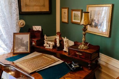 Slatinany, Czech Republic, 17 April 2022:  Castle chateau representative interior with baroque wooden carved furniture, writing table or desk and bookshelves, Photos and figurines, lamp and documents