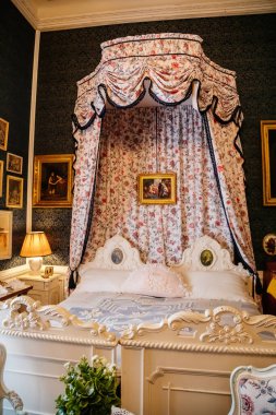 Slatinany, Czech Republic, 17 April 2022: castle chateau representative interior with baroque classic furniture, bedroom with canopy carved wooden bed, paintings and prints on wall, floral pattern