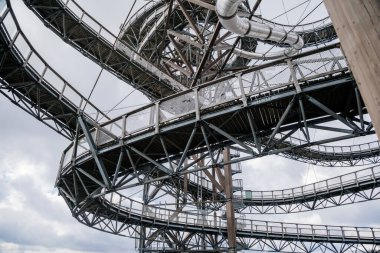 Dolni Morava, Czech Republic, 16 April 2022: Path in the clouds, tourist attraction with spiral platform to observation tower, landscape with forest and sky on mountains, Skywalk with snow