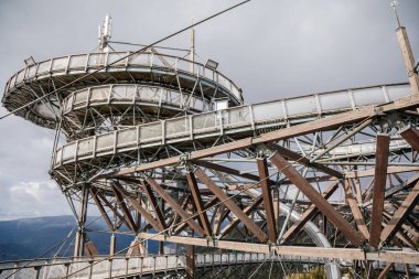 Dolni Morava, Czech Republic, 16 April 2022: Path in the clouds, tourist attraction with spiral platform to observation tower, landscape with forest and sky on mountains, Skywalk with snow