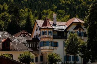 Schwangau, Bavaria, Germany, 3 July 2022: typical bavarian house with wooden balcony and blue shutters at sunny summer day, small village near castles Hohenschwangau and Neuschwanstein in Alps