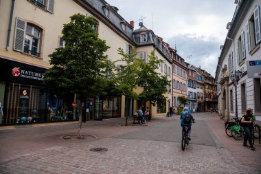 Colmar, Alsace, France, 4 July 2022: town capital of Alsatian wine, narrow picturesque street with medieval colorful houses, Timber framing or post-and-beam construction, people at rue des Clefs